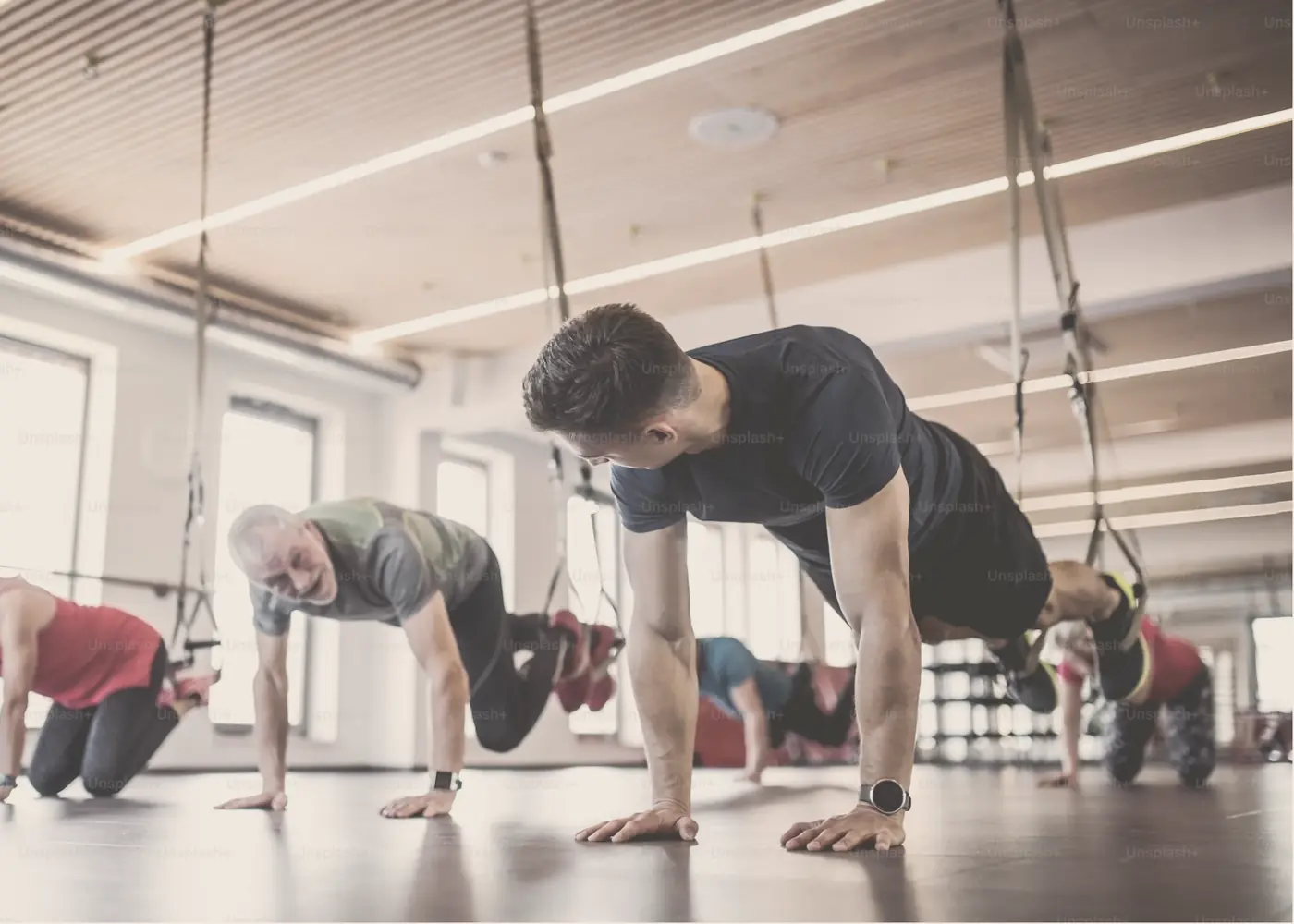 A group class holding a plank on suspension straps