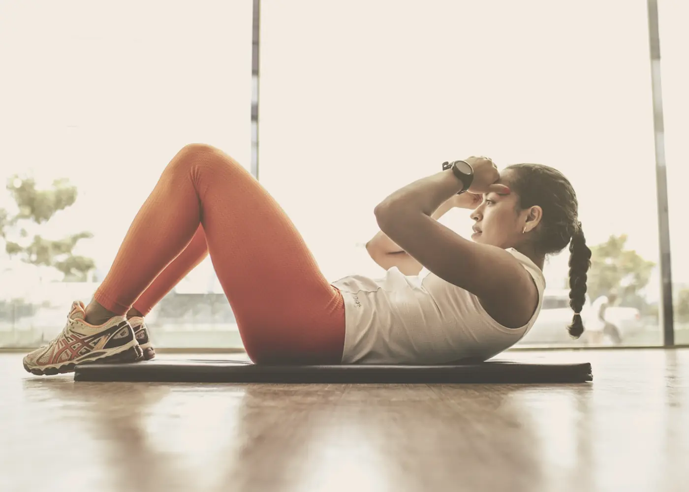 A woman training on a mat wearing a fitness watch