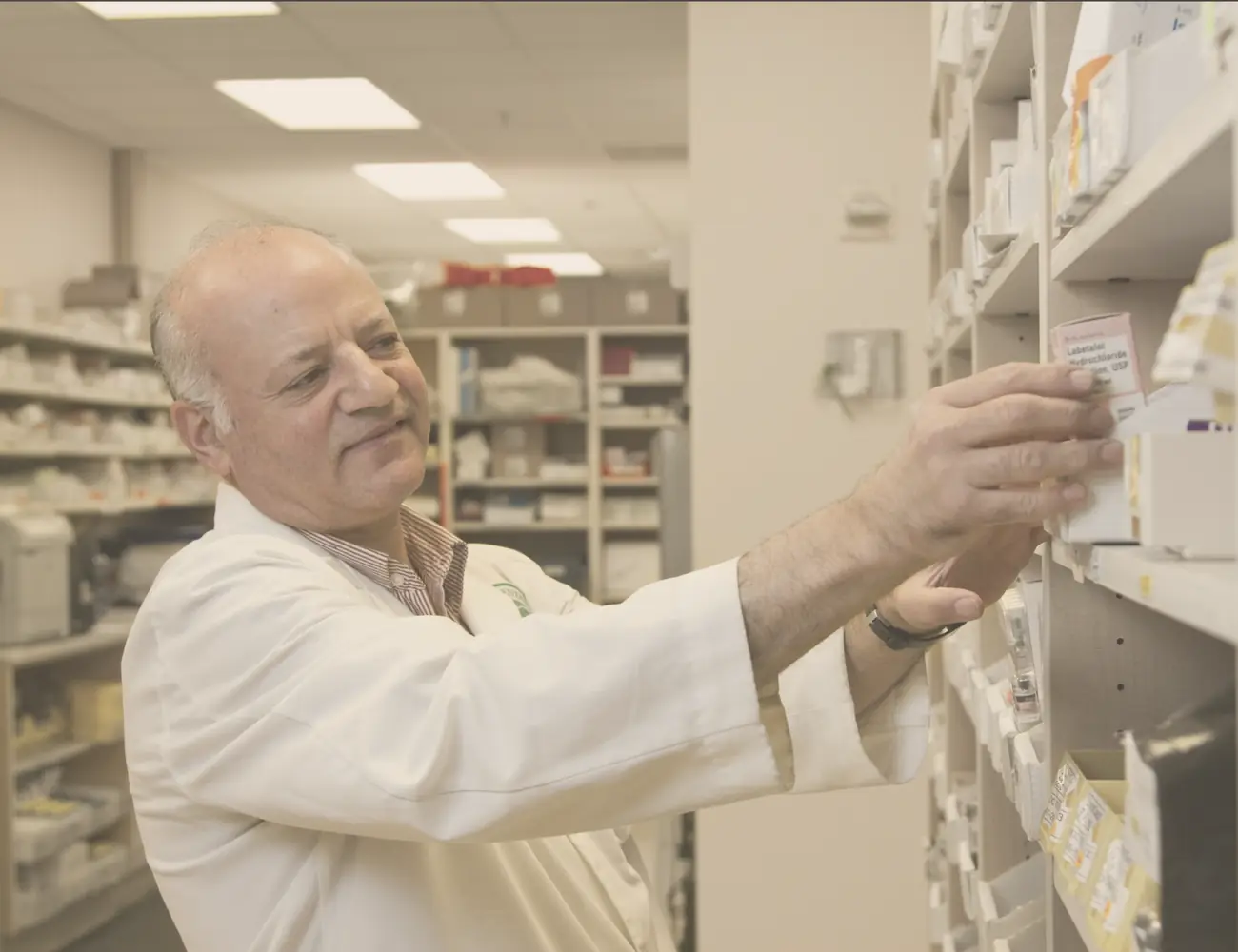 A pharmacist selecting a medication from the dispensary shelves